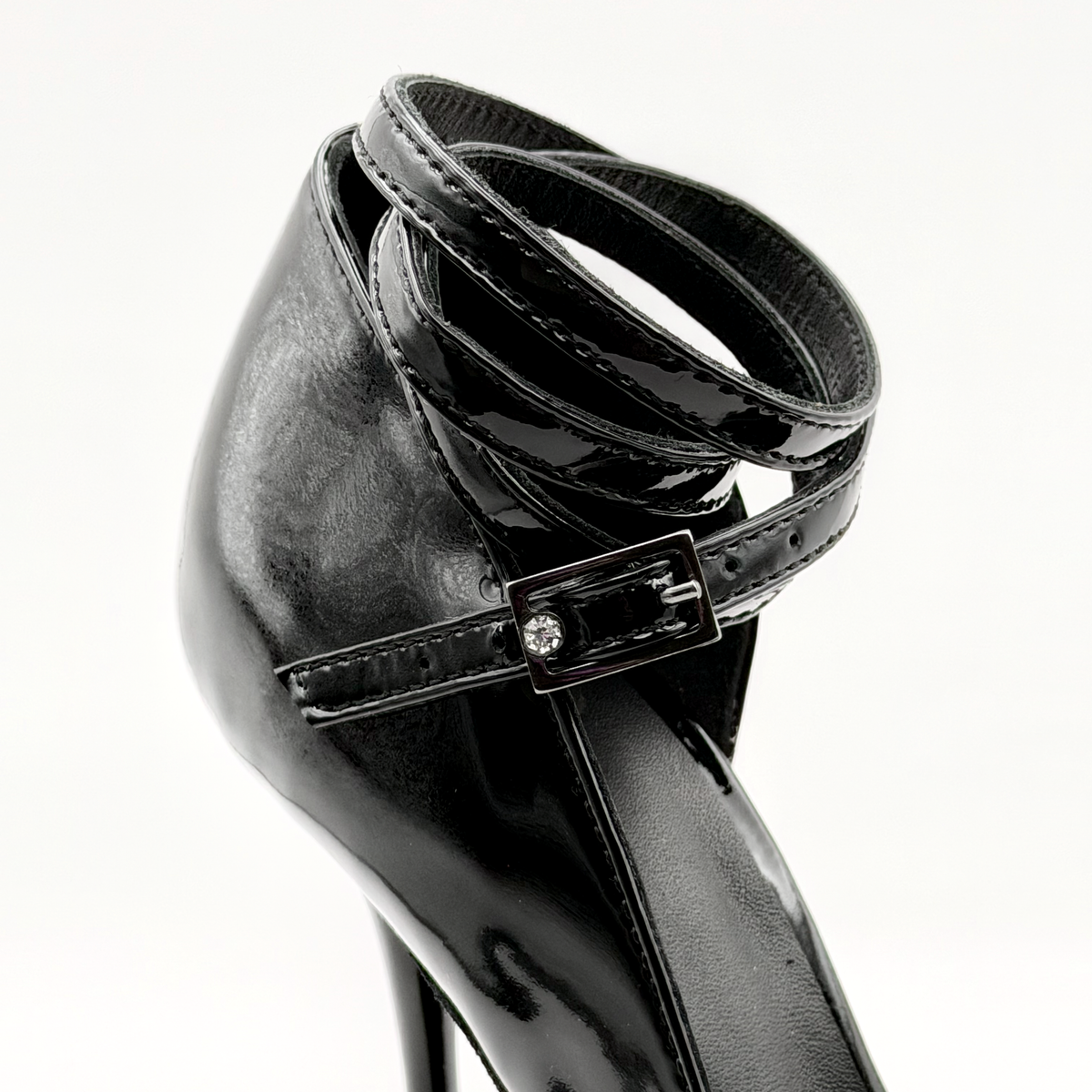 Close-up of the gunmetal rhinestone buckle and black patent wrap strap on the Akvile Noir tango heel