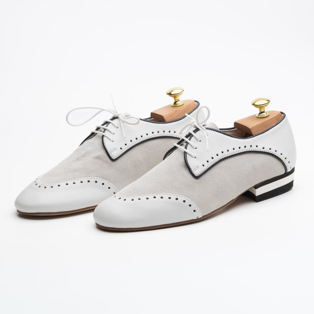 Left side profile of Mono El Dandy men's tango Derby showing the cream suede inlay, white leather surround, brogue perforations along the welt, black piping trim, white laces, and black and white striped low heel against a white background.