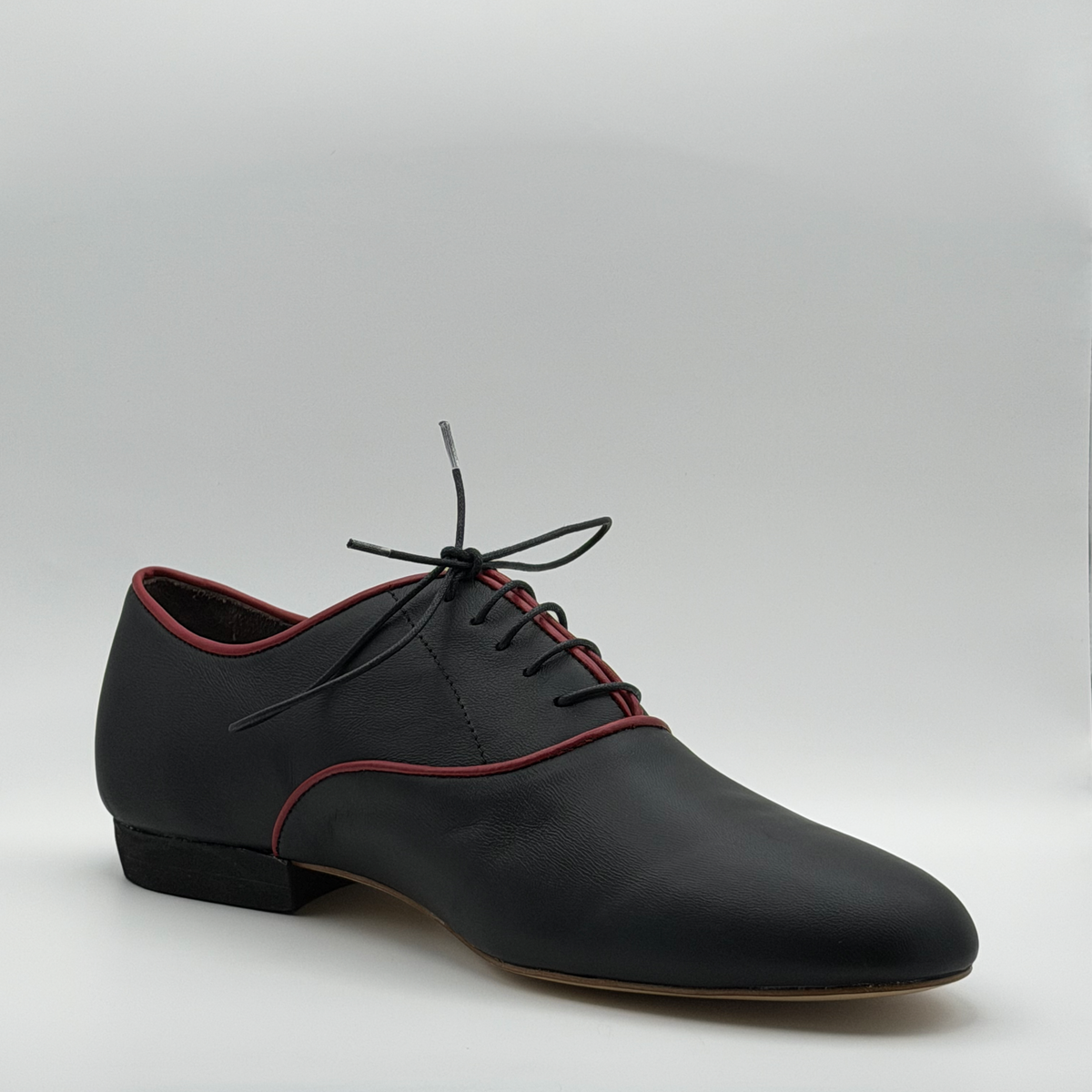 Three-quarter front view of the Mono El Hilo Rojo tango oxford showing the closed lacing with black waxed laces and the almond toe