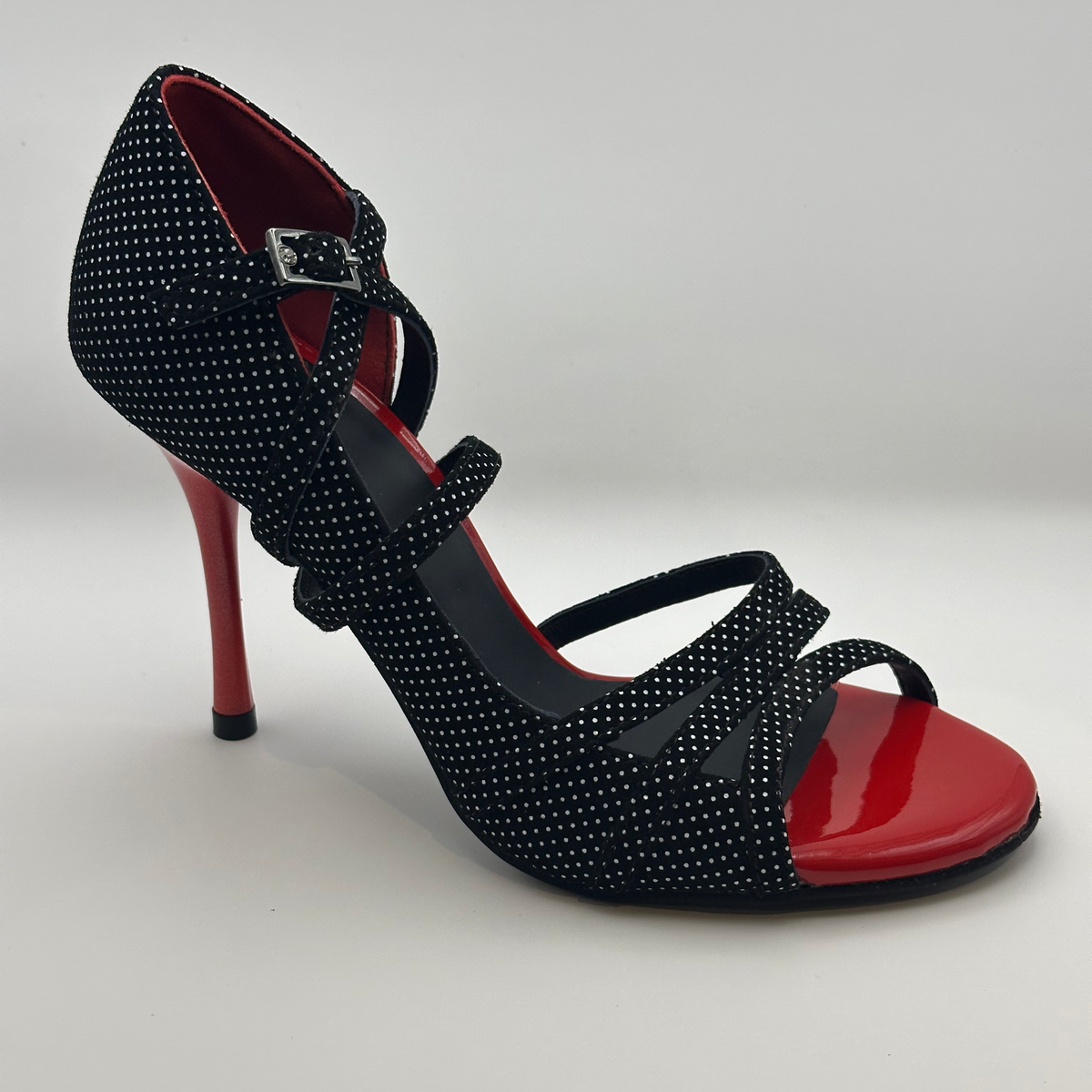 Three-quarter front view of Mono Scarlet Lunares women's tango heel with black and white polka dot upper, red patent toe cap, buckled ankle strap, and slender red stiletto heel.