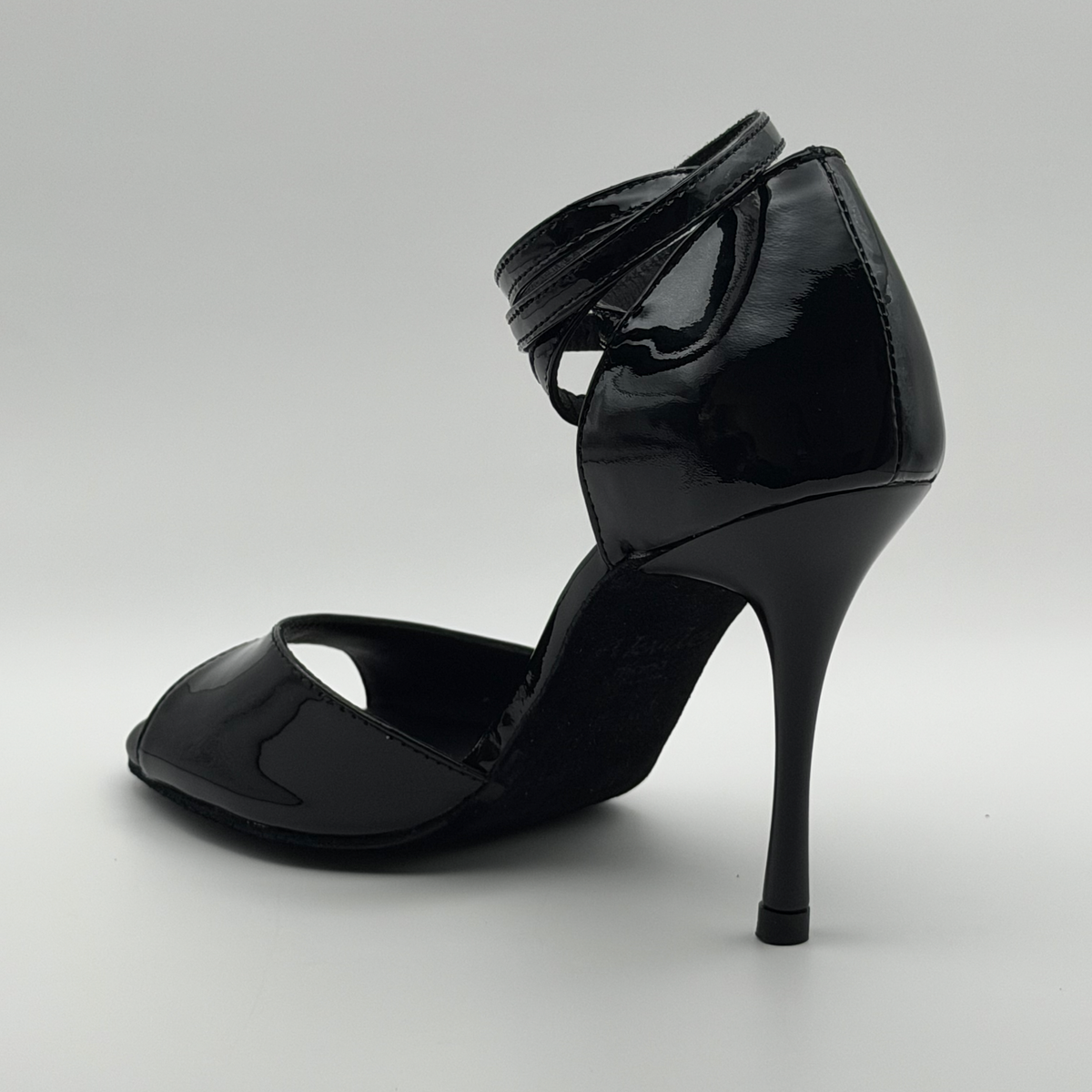 Front inner angle of the Akvile Noir women's tango heel in black patent leather with the ankle strap wrapped around the heel counter