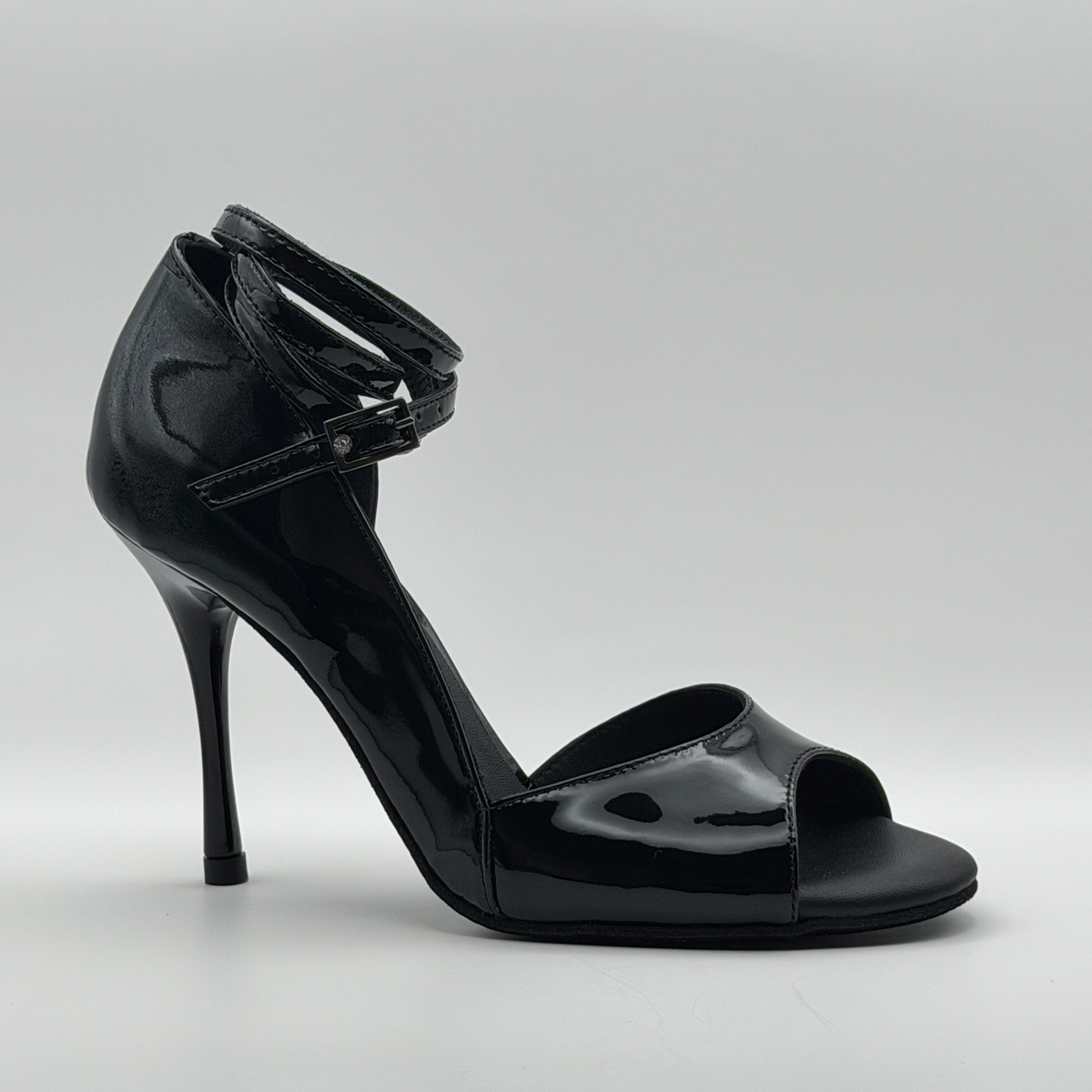 Angled side view of the Akvile Noir black patent tango heel with the rhinestone buckle on the ankle strap and the open toe