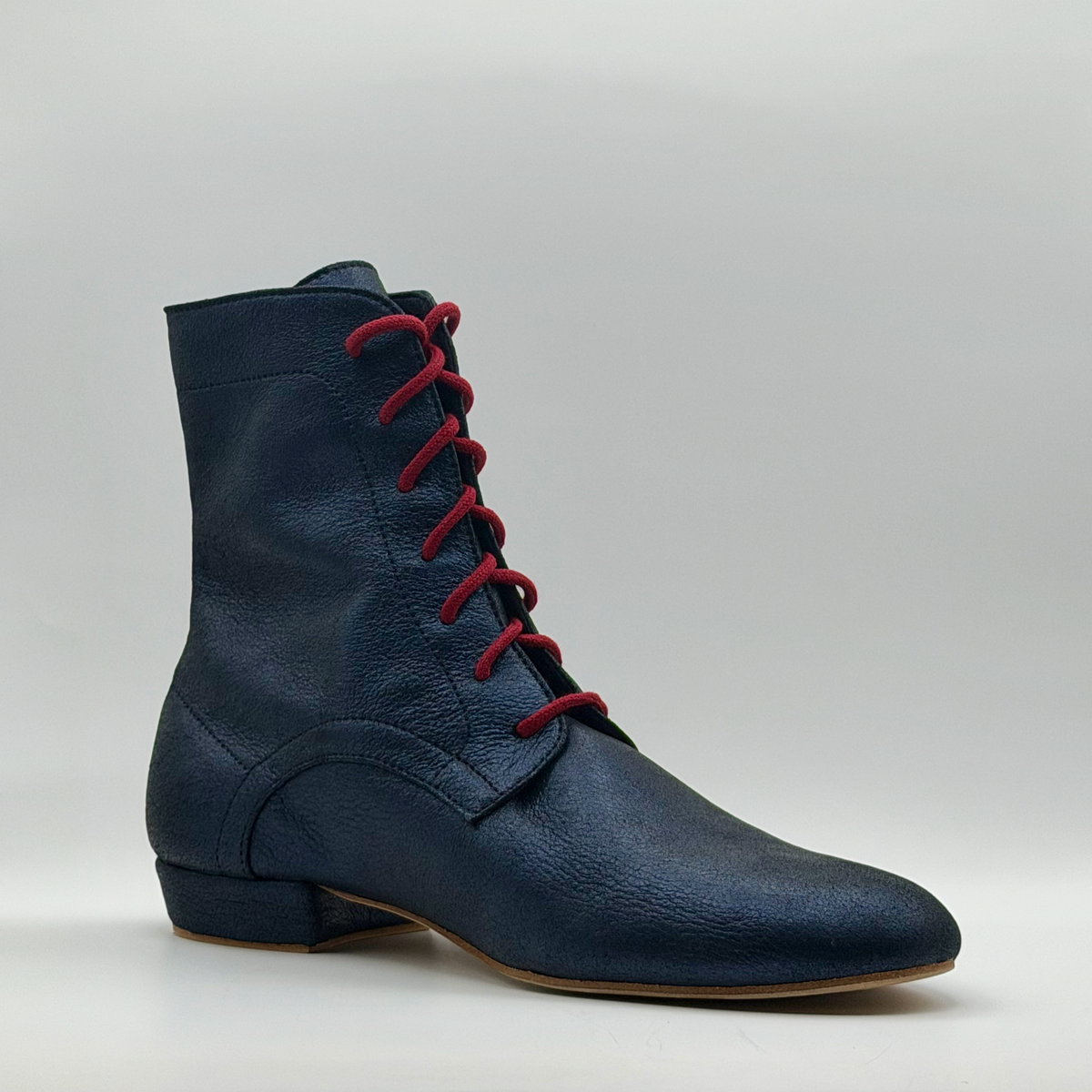 Three-quarter front view of the Mono Bleu Marine tango boot showing the red cotton laces, the almond toe, and the burnished navy leather