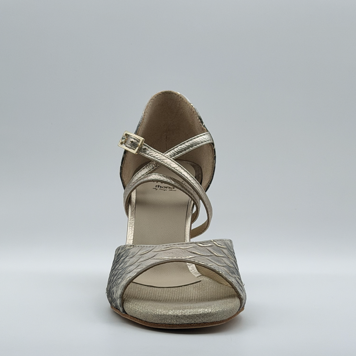 Front view of the Mono Ceniza Dorada tango heel showing the crossed metallic gold straps over the instep and the gradient of the snake-embossed upper