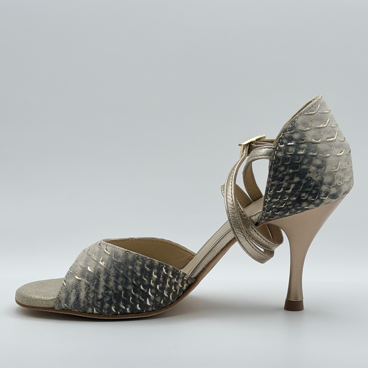 Inner side profile of the Mono Ceniza Dorada tango heel showing the full gray-to-bone gradient across the upper and the closed embossed heel cage