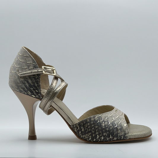 Side profile of the Mono Ceniza Dorada women's tango heel in gray and bone snake-embossed leather, showing the metallic gold wrap strap crossing the instep and the flared heel