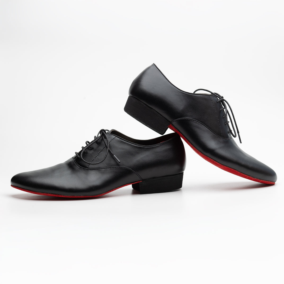 Pair of Mono El Caballero tango oxfords in side view, one raised on its heel, showing the black stacked heel and red suede sole edge