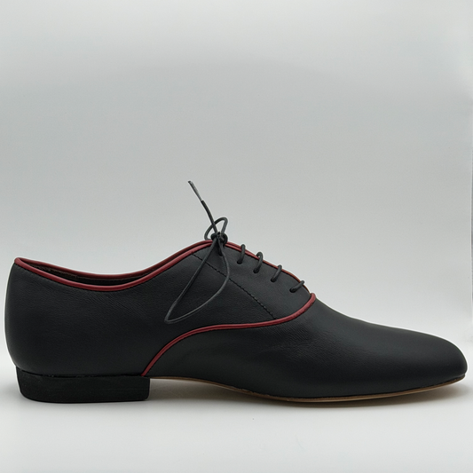 Side profile of the Mono El Hilo Rojo men's tango oxford in black leather, showing the fine red piping tracing the topline and panel curves