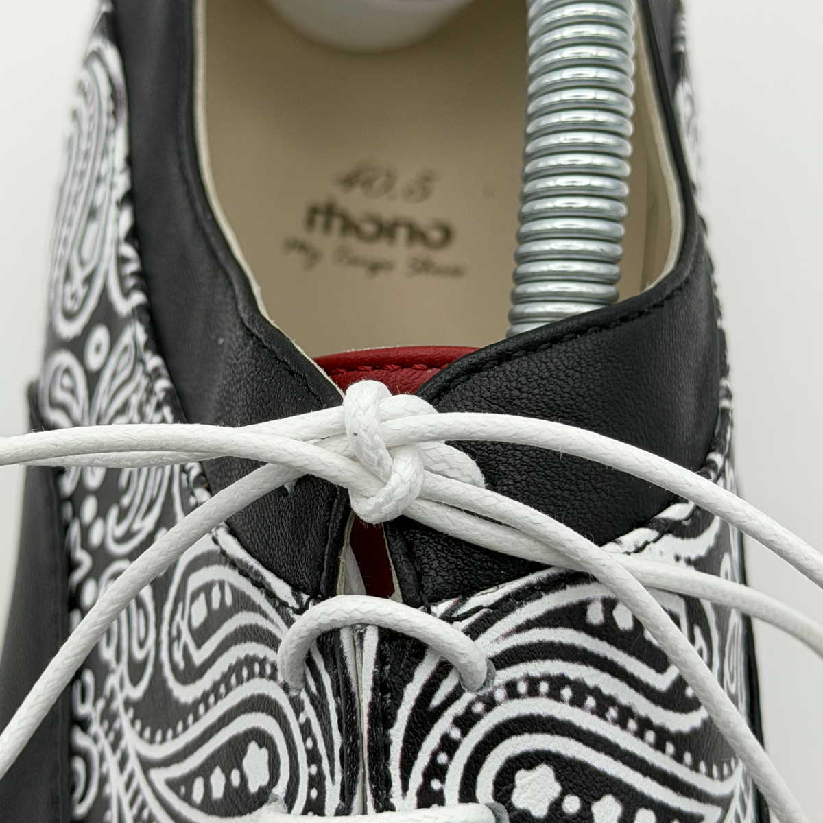 Close-up of the Mono El Pañuelo tango oxford showing the closed lacing, paisley print detail, and red leather tongue lining
