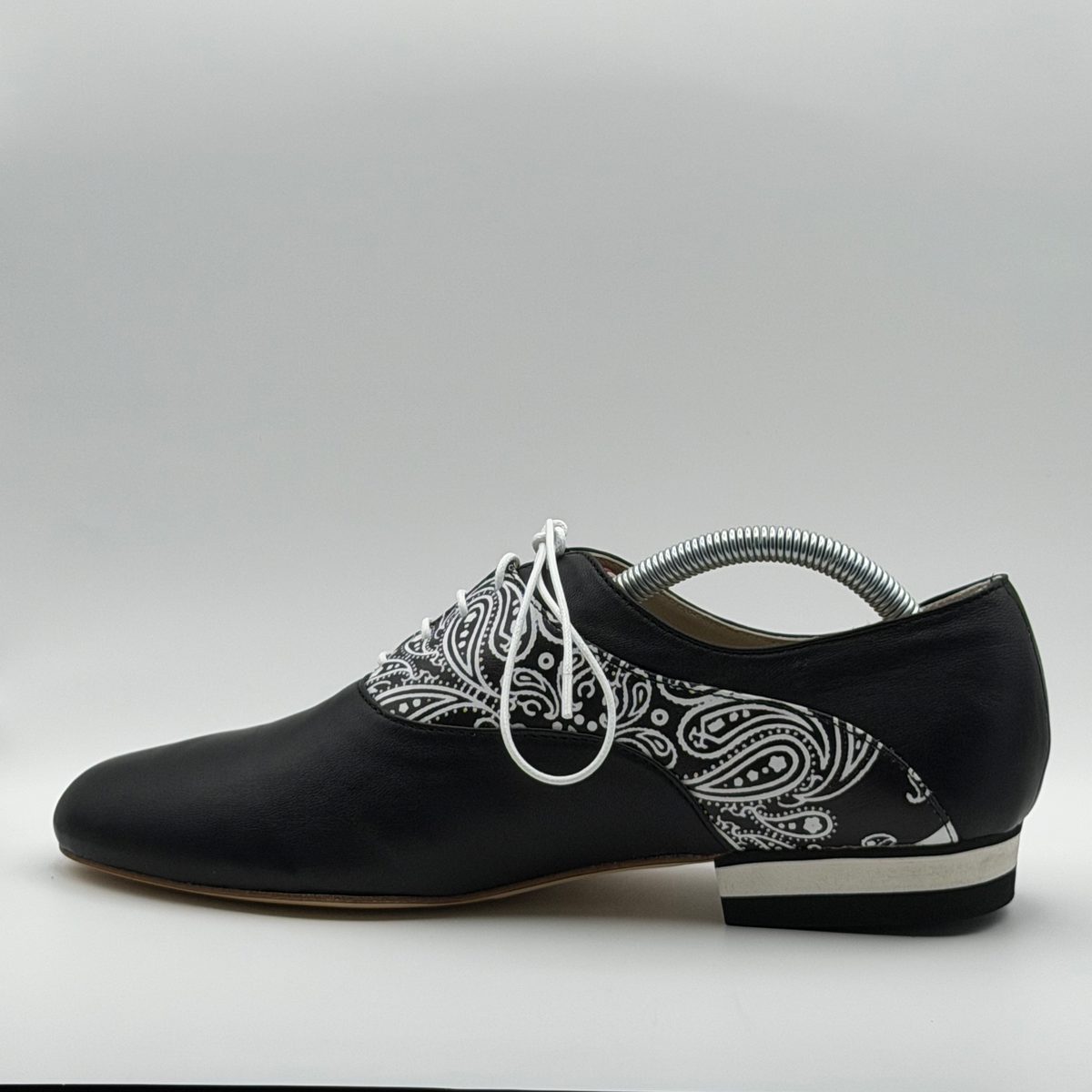 Opposite side profile of the Mono El Pañuelo tango oxford showing the black-and-white striped heel stack and leather sole