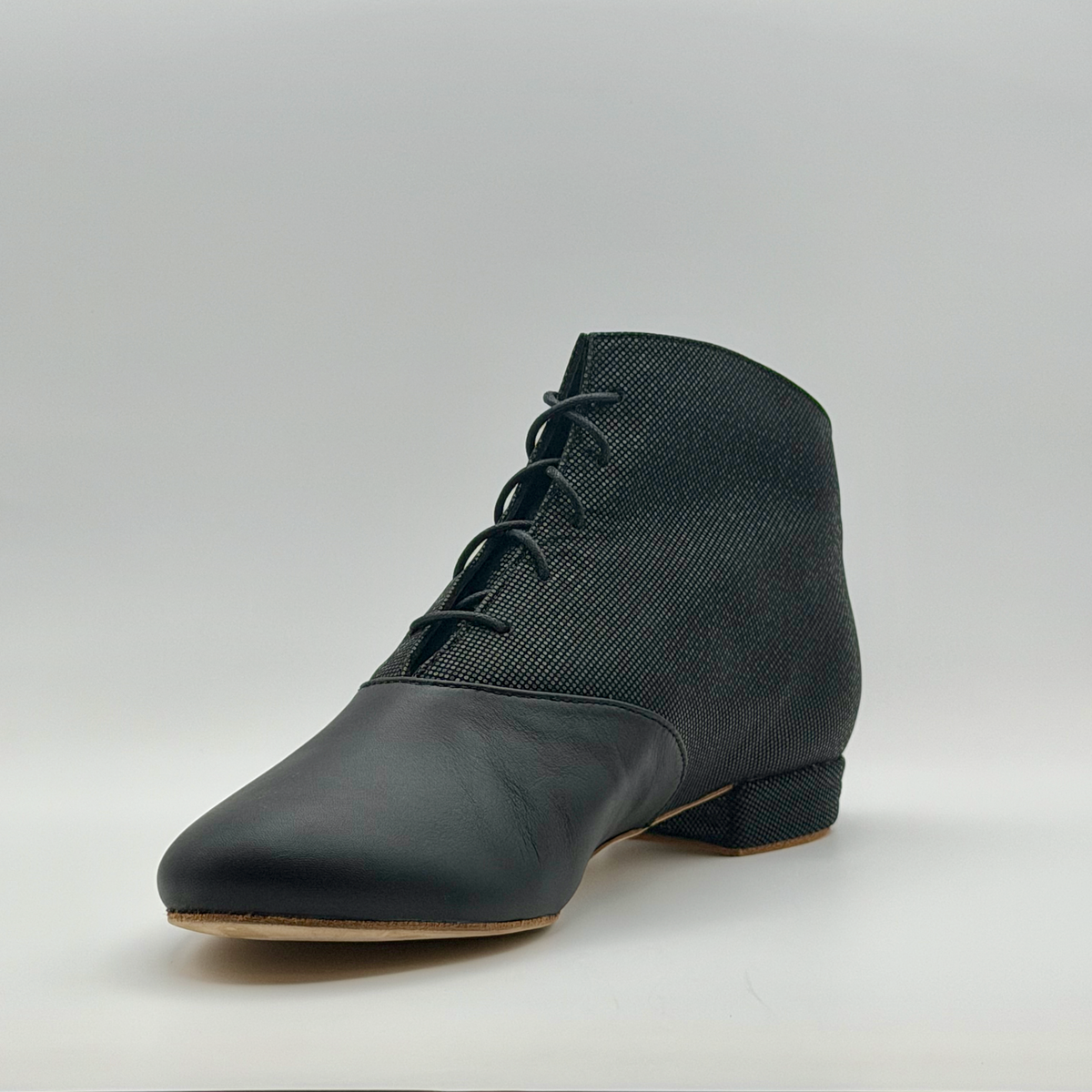 Three-quarter front view from the other side of the Fumée Bottine tango bootie, showing the laced front and smoky micro-dot shaft above the black leather toe