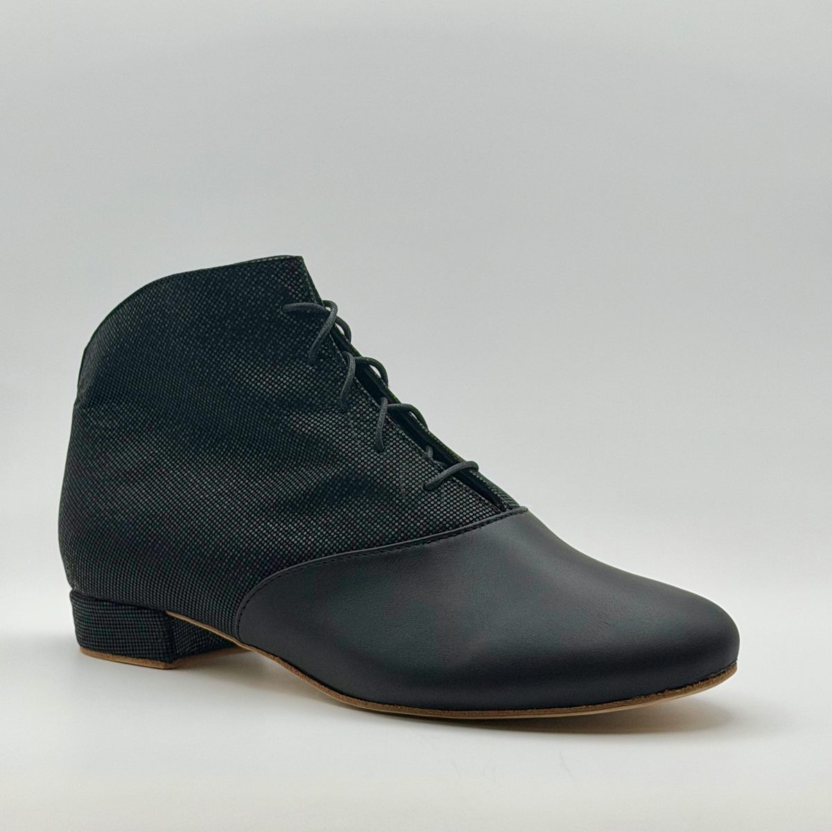 Three-quarter front view of the Fumée Bottine women's tango bootie showing the lace-up front, almond toe, and two-tone black leather and micro-dot texture