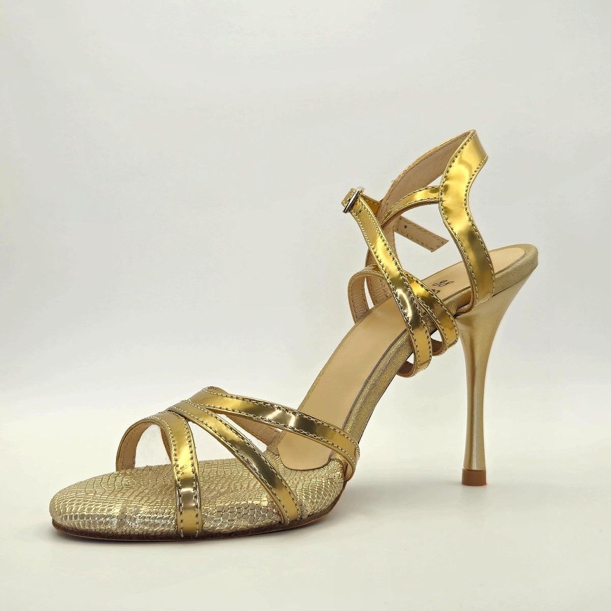 Side profile of Mono Gilded Serpent women's tango sandal facing left, showing the golden metallic multi-strap vamp and slender stiletto heel.