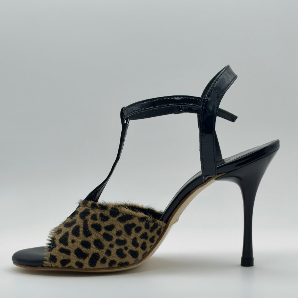 Left side profile of Mono La Fiera tango sandal showing the black patent leather T-bar strap, leopard pony hair toe band texture, and the clean heel-to-toe line of the slim stiletto.