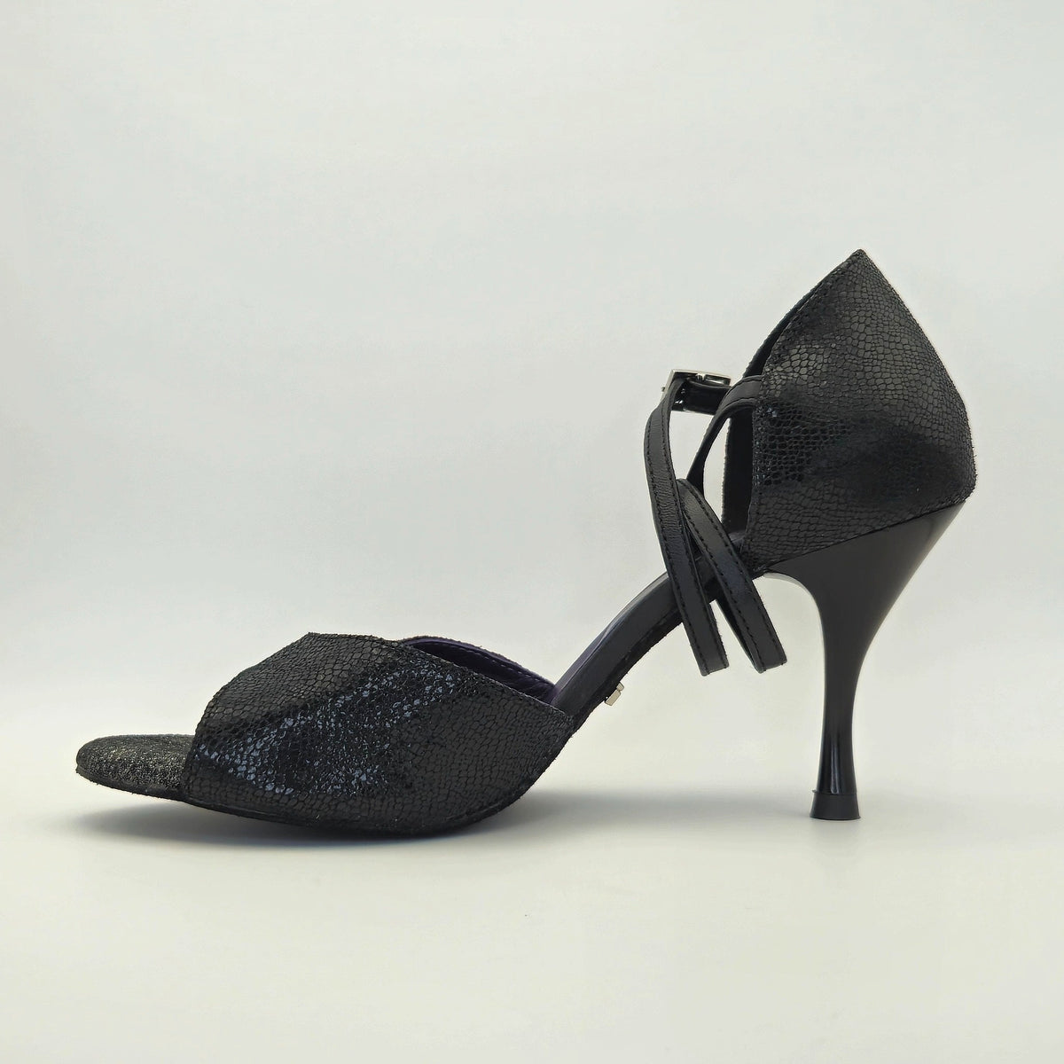 Side profile of Mono Midnight Mystique women's closed-heel tango shoe facing left, showing the black shimmer textured leather upper and crossover ankle strap over the closed heel counter.
