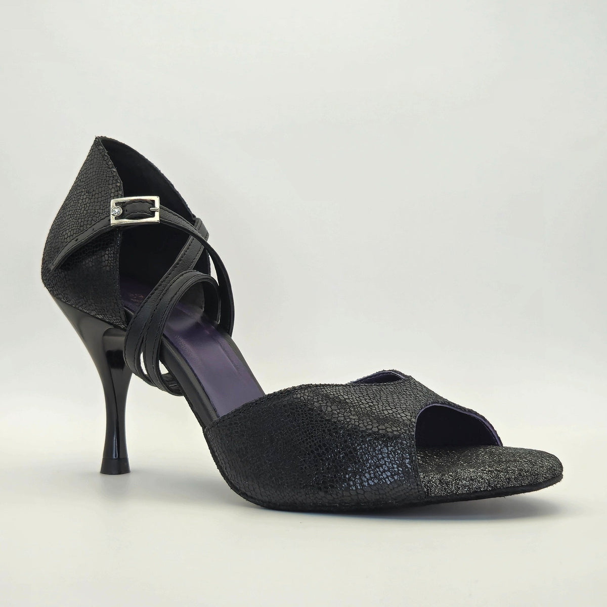 Side profile of Mono Midnight Mystique women's closed-heel tango shoe facing right, showing the crossover ankle strap and deep violet insole against the black shimmer upper.