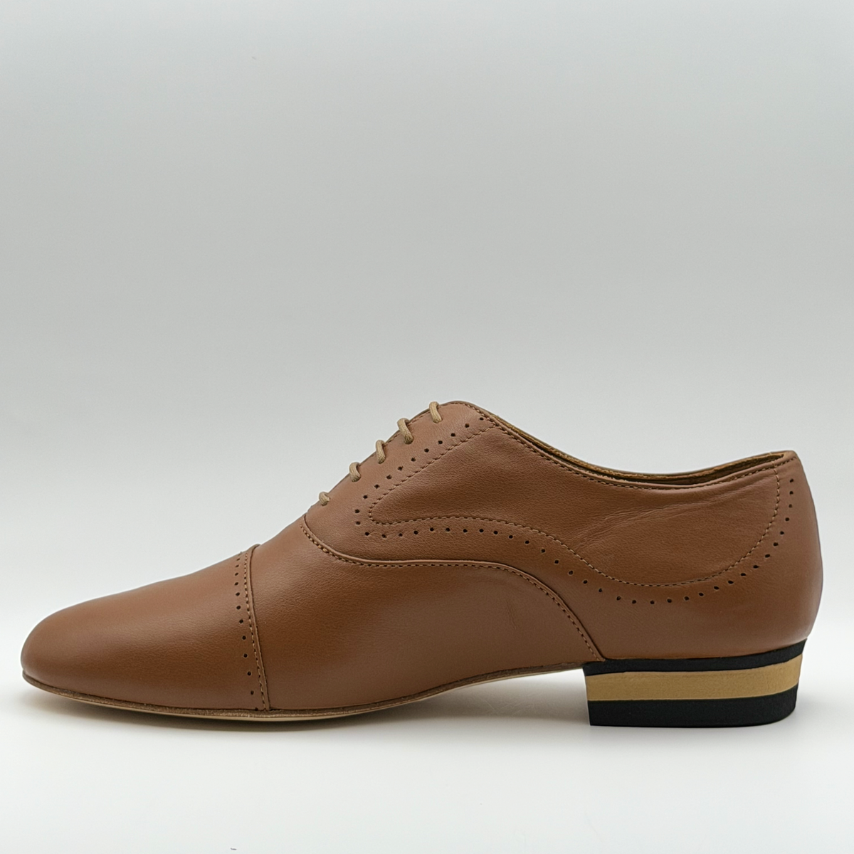 Inner side view of the Tabacco tango oxford showing the sweeping line of perforations and the black and natural striped low heel