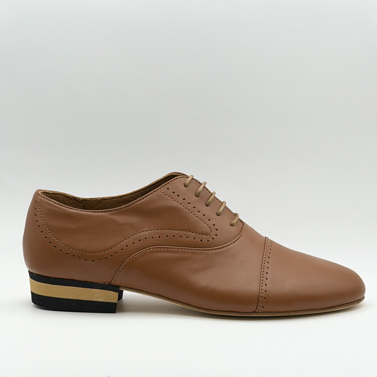 Side profile of the Mono Tabacco men's tango oxford in tobacco-brown leather, showing the perforated cap toe, curved side broguing, closed lacing, and striped low heel